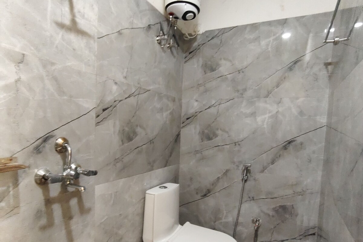 A bathroom with a toilet, shower, and a toilet paper holder.
