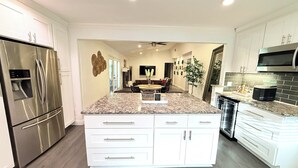A modern kitchen with white cabinetry, stainless steel appliances, and a granite countertop. - Welcome to The Royal Ranch: Your Ultimate Retreat in Central Dallas! (Dallas)
