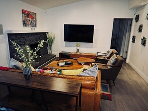 A living room with a fireplace, a flat-screen TV, a coffee table, and a sofa. - Welcome to The Royal Ranch: Your Ultimate Retreat in Central Dallas! (Dallas)