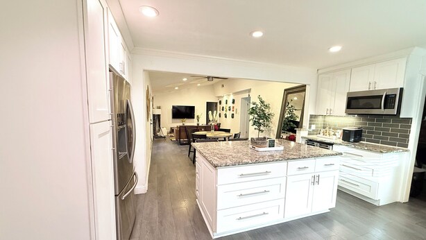 A modern kitchen with white cabinetry, a granite countertop, and a built-in microwave. - Welcome to The Royal Ranch: Your Ultimate Retreat in Central Dallas! (Dallas)