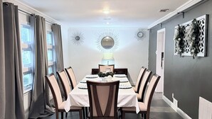 A dining room with a table set for six, surrounded by chairs, a chandelier, and decorative wall art. - Welcome to The Royal Ranch: Your Ultimate Retreat in Central Dallas! (Dallas)