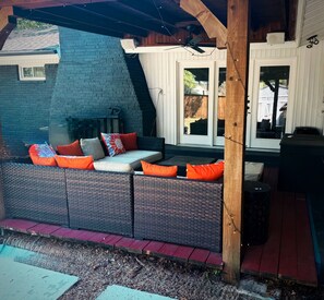 An outdoor patio with wicker furniture, a ceiling fan, and a brick wall. - Welcome to The Royal Ranch: Your Ultimate Retreat in Central Dallas! (Dallas)