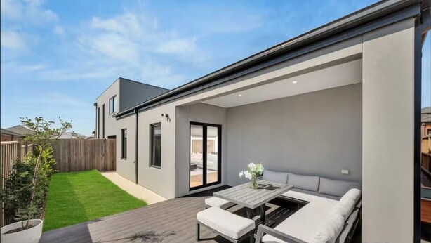 A modern house with a patio, a sliding glass door, and a small garden.