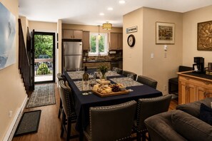 A dining area with a long table, chairs, a buffet with cheese and crackers, a wine bottle, and a clock on the wall. - Camelback Family Escape | Ski-In/Out + Game Room (Tannersville)