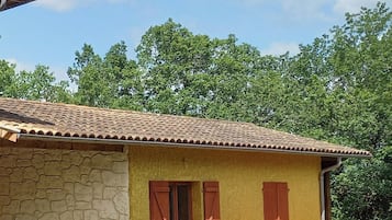 Ein zweistöckiges Haus mit Steinverkleidung, einem Ziegeldach und einem kleinen Garten mit Blumentöpfen.