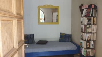 Ein Zimmer mit einem Bett, einem Spiegel und einem Bücherregal.
