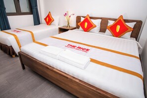 A hotel room with two beds, each with a white bedspread and orange trim. There is a wooden headboard, a nightstand with a vase of flowers, and a window with curtains. - The Rice Hotel&Tour - 39 Nguyen Trai No4 (Ho Chi Minh City)