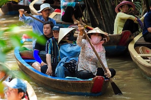 A group of people in a traditional boat, likely engaged in a cultural or tourist activity. - The Rice Hotel - Ben Thanh (Ho Chi Minh City)