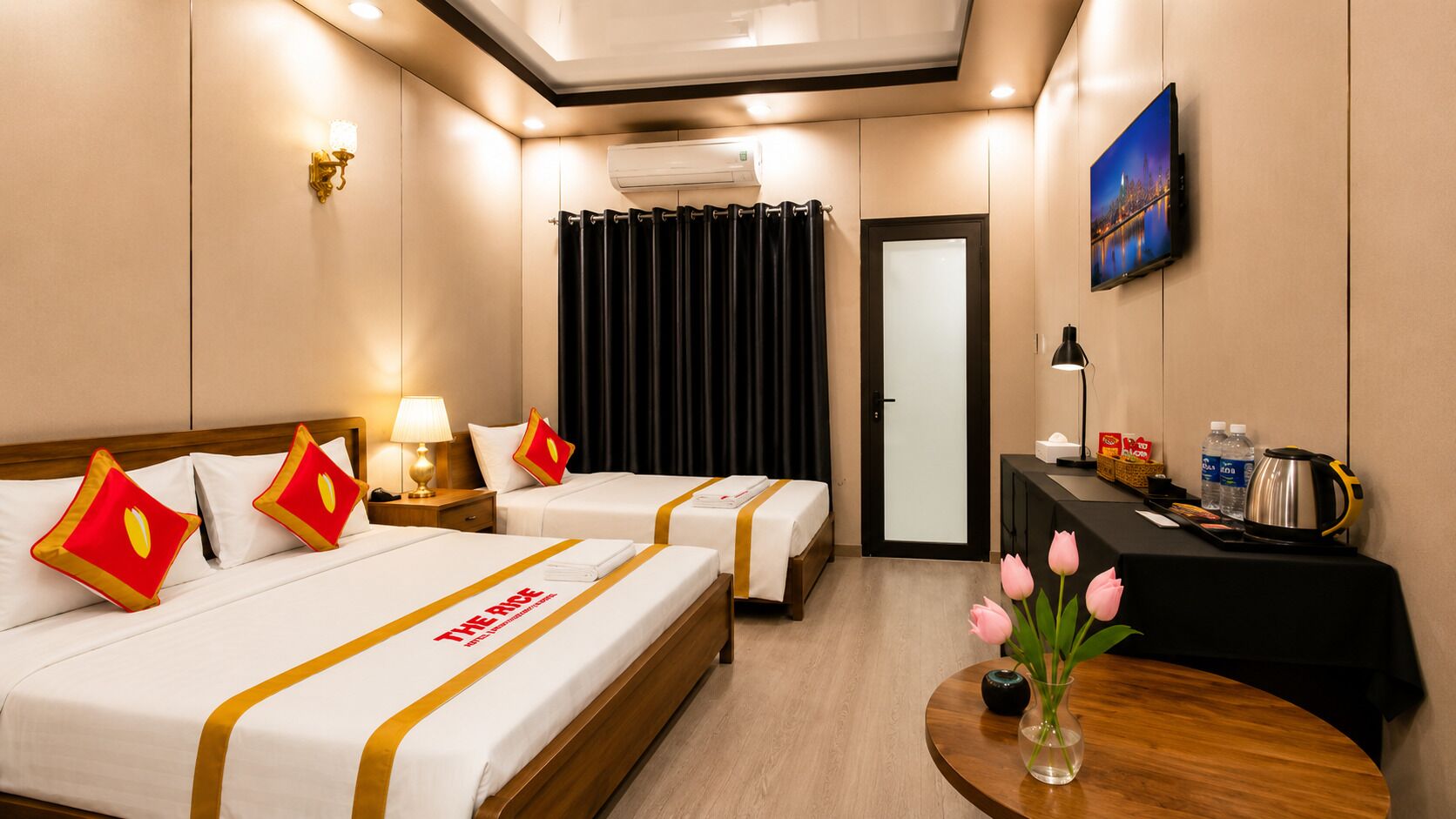 Habitación de hotel con dos camas, un escritorio, un televisor y una ventana con cortinas.