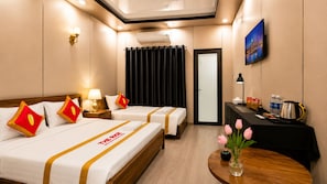 Een hotelkamer met twee bedden, een bureau, een televisie en een raam met gordijnen.