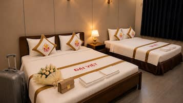 A hotel room with two beds, a suitcase, and a bouquet of flowers.
