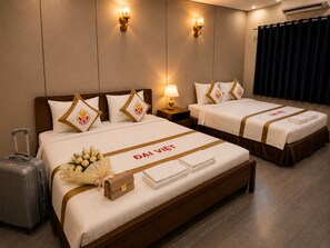 Une chambre d’hôtel avec deux lits, une valise et un bouquet de fleurs.