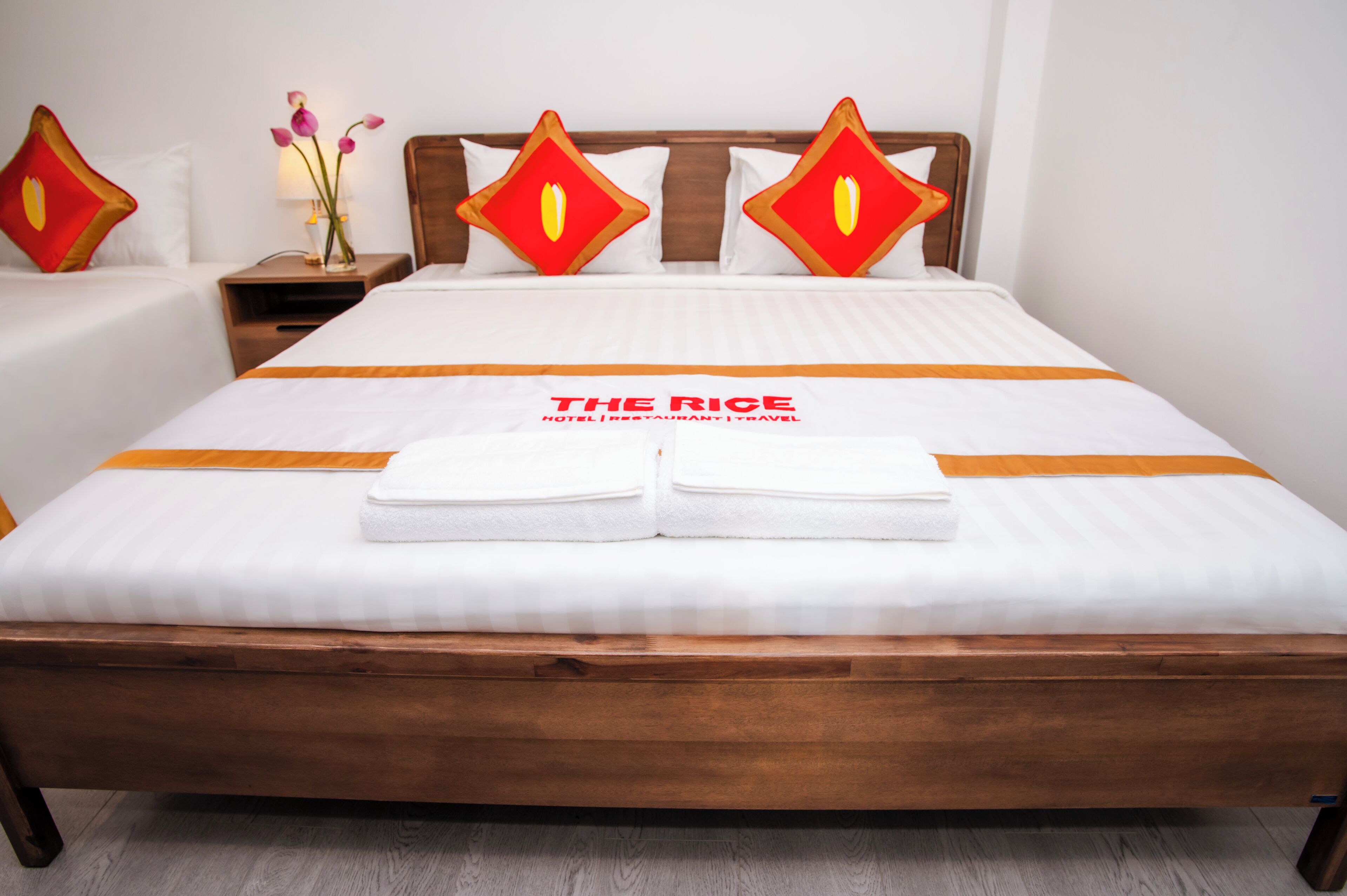 A neatly made bed with a branded bedspread, pillows, and a folded towel.