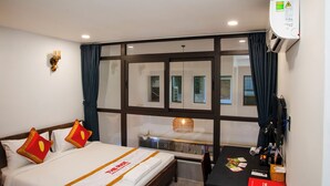Una habitación de hotel con cama, escritorio, ventana y aire acondicionado instalado en la pared.