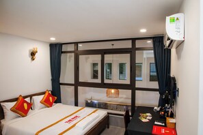 A hotel room with a bed, a desk, a window, and a wall-mounted air conditioner. - The Rice Hotel&Tour - 39 Nguyen Trai No4 (Ho Chi Minh City)