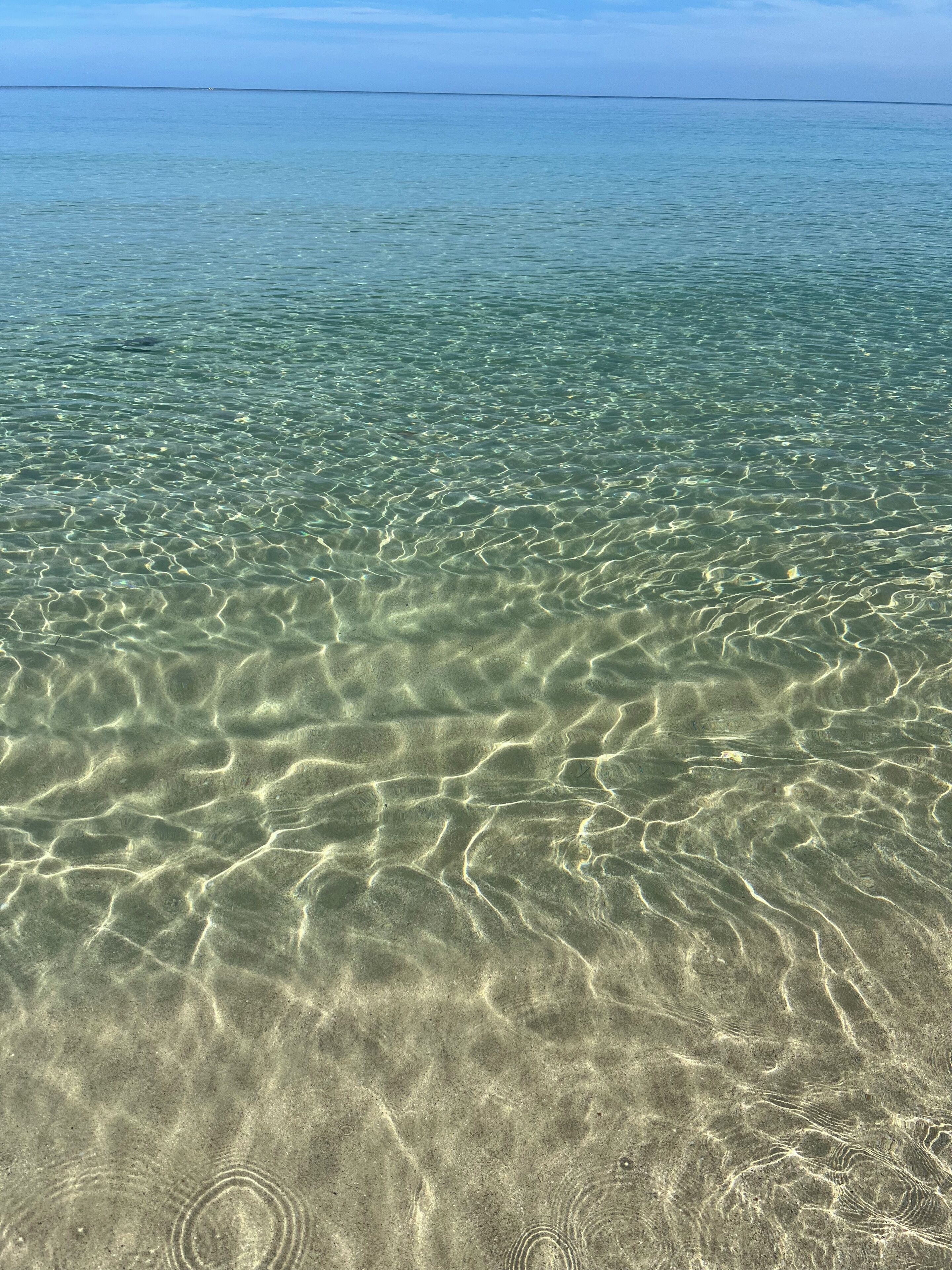 Eau claire et peu profonde, où l’on peut distinguer les motifs formés par le sable.