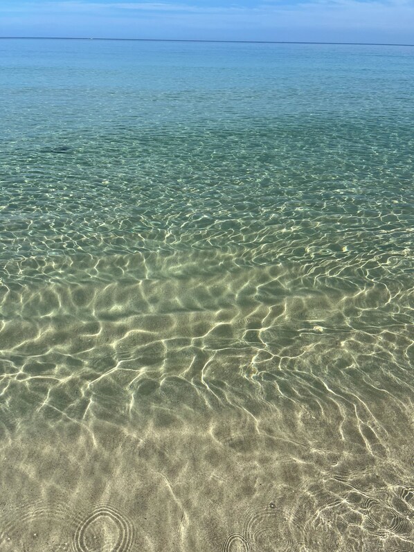 Klares, flaches Wasser mit deutlich sichtbaren Sandmustern.
