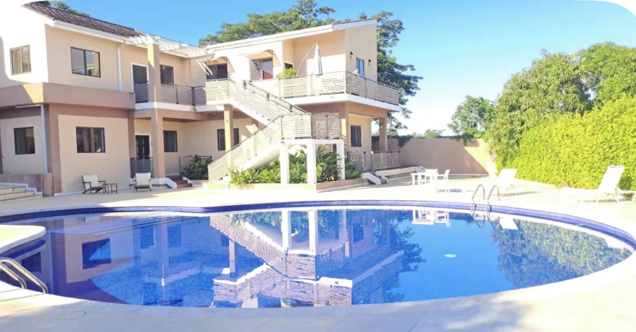 Un bâtiment à deux étages doté d’une piscine, d’un espace extérieur aménagé et d’un escalier menant à l’étage supérieur.