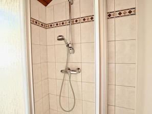 Ducha con cabezal de ducha manual y cabezal de ducha fijo, ambos montados en una pared con azulejos.
