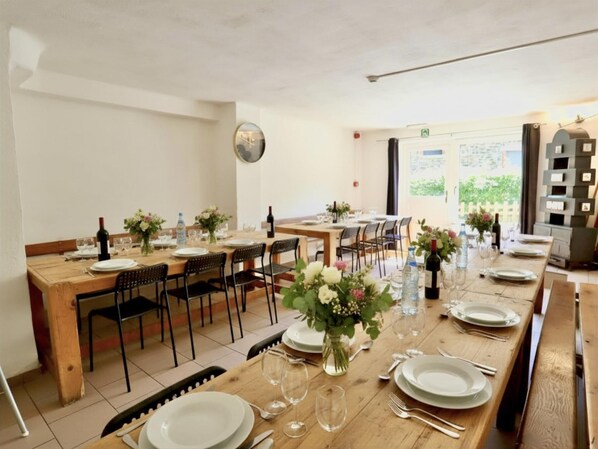A dining area with wooden tables and chairs, set with plates, glasses, and bottles. - Pretty group house with a sauna, games & garden (Lierneux)