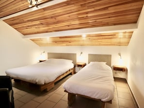 Ein Zimmer mit zwei Holzbett, jeweils mit einem Nachttisch und einer Wandlampe.