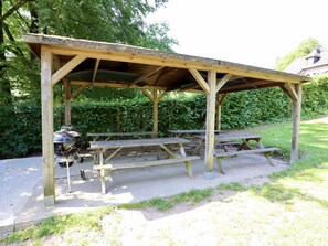 A wooden picnic shelter with benches and a barbecue grill. - Pretty group house with a sauna, games & garden (Lierneux)