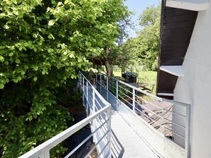 Eine Metallbrücke mit Geländern, die zu einem Gebäude mit dunkler Fassade führt.