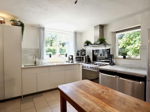 Una cocina moderna con armarios blancos, una mesa de madera y vistas al exterior.