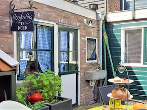 A brick building with a sign reading 'Stoofpauling TE KOP,' a window with a checkered curtain, a red kettle, and a table with pastries. - Authentic fisherman's house in the heart of Edam (Edam)