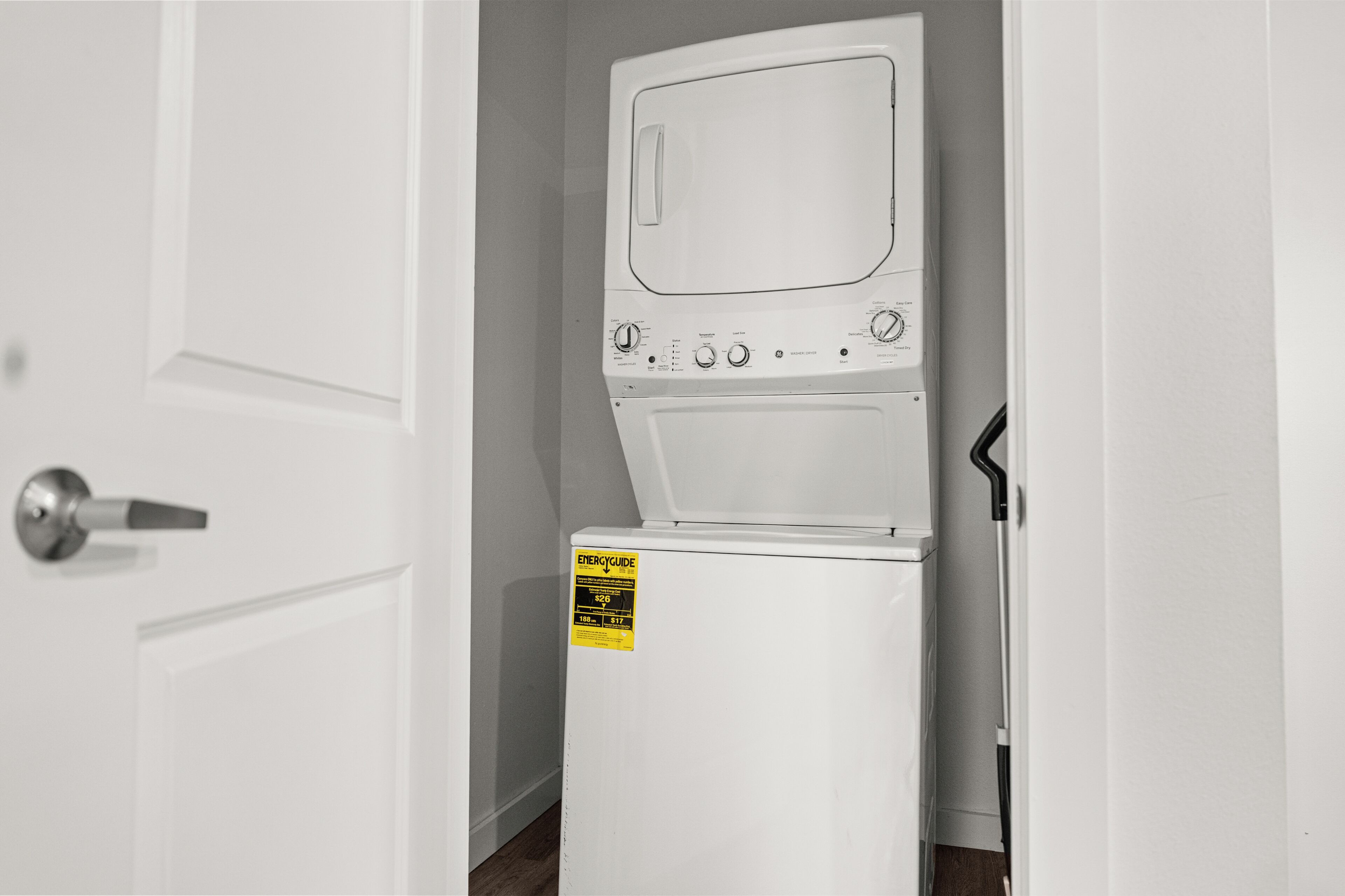 A compact washer and dryer unit with an ENERGY GUIDE label, a door with a silver handle, and a wooden floor.