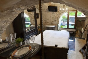 Ein rustikaler Steinraum mit einem Bett, einem Tisch und einem Spiegel.