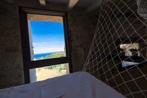 Ein Zimmer mit einem Bett, einem Fenster mit Landschaftsblick und einem Bereich mit Moskitonetz.