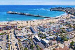 Een kuststadsgezicht met een pier die in de oceaan uitloopt, strand en een combinatie van woon- en bedrijfsgebouwen.