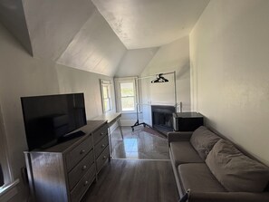 Een moderne woonkamer met een flatscreen televisie, een bank, een open haard en een groot raam.