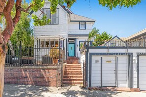 A two-story house with a garage, a blue door, and a brick staircase leading to the entrance. - Steps to Beach & Boardwalk, Cozy Room, Fast WiFi, Private Bath, Coffee+Snacks #4 (Santa Cruz)