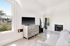 A modern living room with a flat-screen TV, a grey sofa, and a fireplace. - Steps to Beach & Boardwalk, Cozy Room, Fast WiFi, Private Bath, Coffee+Snacks #4 (Santa Cruz)