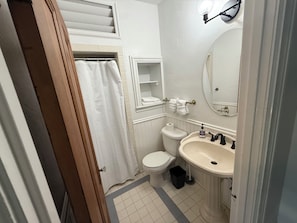 Een badkamer met toilet, wastafel en spiegel.