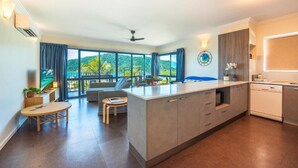 Eine moderne Küche mit einer zentralen Kochinsel, großen Fenstern und Blick auf Grünflächen.