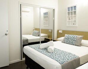 A hotel room with a bed, bedside tables, a mirror, and a window.
