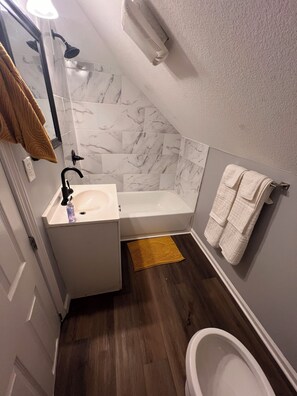 A bathroom with a sink, mirror, shower, and bathtub. - Spacious centrally located 4-bedroom house in charming Kansas City (Kansas City)