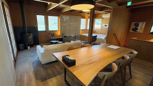 A wooden interior with a large dining table, white sofa, and a fireplace. - REN HANARE Hakuba (Hakuba)