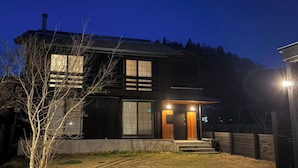 A two-story building with a dark exterior, large windows, and a visible entrance with steps. - REN HANARE Hakuba (Hakuba)