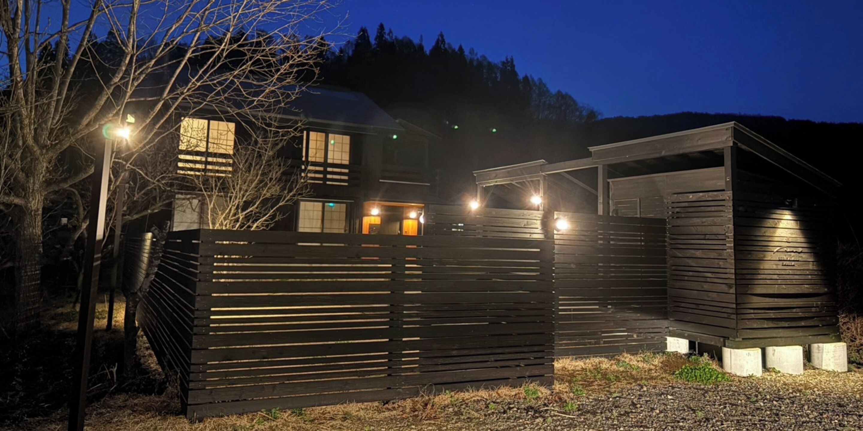 A modern building with a sloped roof, multiple windows, and a wooden fence.