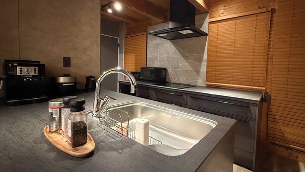 A modern kitchen with a stainless steel sink, wooden cabinets, a built-in stove, and a microwave. - REN HANARE Hakuba (Hakuba)