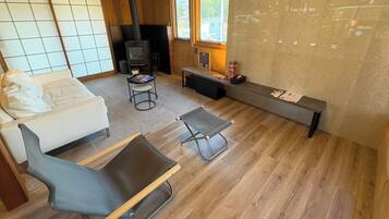 A modern living room with a sofa, a black chair, a small table, a fireplace, and a window with a view.
