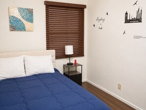 A bedroom with a bed, a nightstand, a wall art piece, and a wall decal. - Sleepy Getaway in the Hills (Burbank)