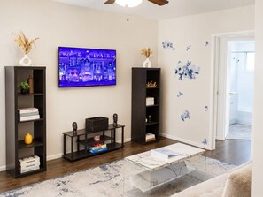 A living room with a TV, bookshelves, a coffee table, and decorative wall stickers. - Sleepy Getaway in the Hills (Burbank)