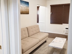 A beige sofa, a marble coffee table, a painting, and a window with blinds. - Sleepy Getaway in the Hills (Burbank)