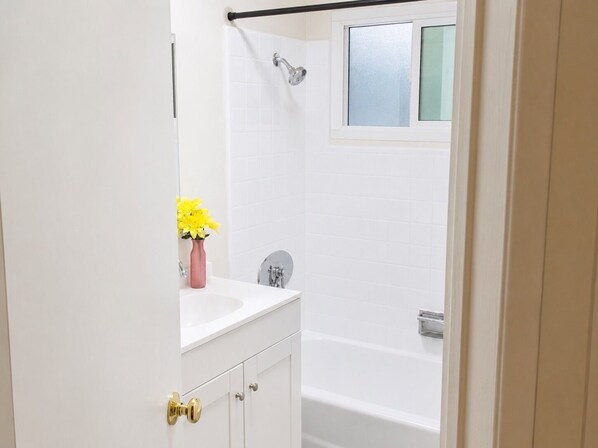 A bathroom with a white sink, a mirror, a shower, and a window. - Sleepy Getaway in the Hills (Burbank)