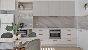 Una cucina moderna con mobili bianchi, una schiena di marmo e un forno incassato.